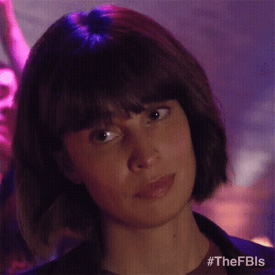 A Woman With Short Hair And Bangs Is Looking At The Camera In A Club . GIF