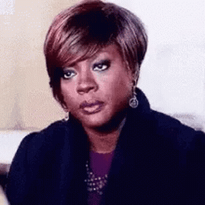 A Woman With Short Hair Is Making A Funny Face While Wearing A Black Jacket And Earrings . GIF