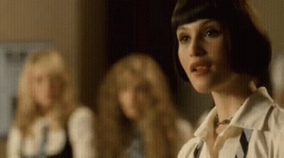 A Woman With Short Hair Is Standing In Front Of A Group Of Women . GIF