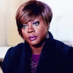 A Woman With Short Hair Is Wearing A Purple Shirt And A Black Coat . GIF
