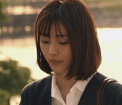 A Woman With Short Hair Is Wearing A Suit And A White Shirt And Is Looking Down . GIF