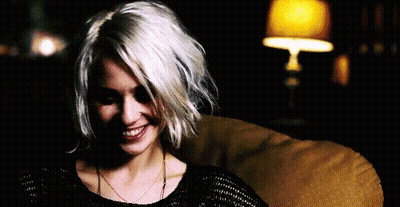A Woman With Short White Hair Is Sitting On A Couch And Smiling . GIF