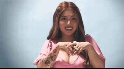 A Woman With Tattoos On Her Arm Making A Heart Shape With Her Hands GIF