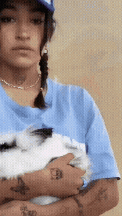 A Woman With Tattoos On Her Arms Is Holding A White Rabbit . GIF