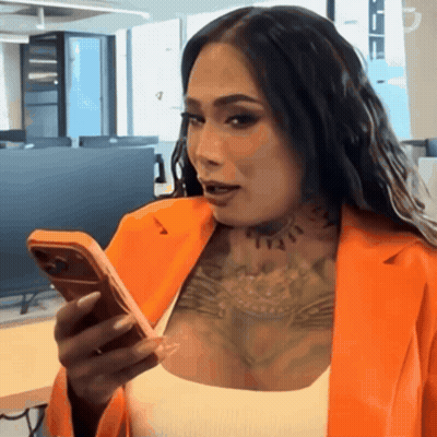 A Woman With Tattoos On Her Chest Is Looking At Her Phone GIF