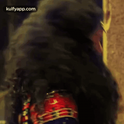 A Woman With Very Long Black Hair Is Standing In Front Of A Door . GIF