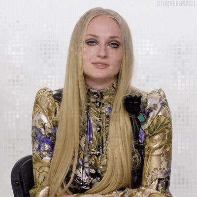 A Woman With Very Long Blonde Hair Is Wearing A Gold And Purple Dress GIF