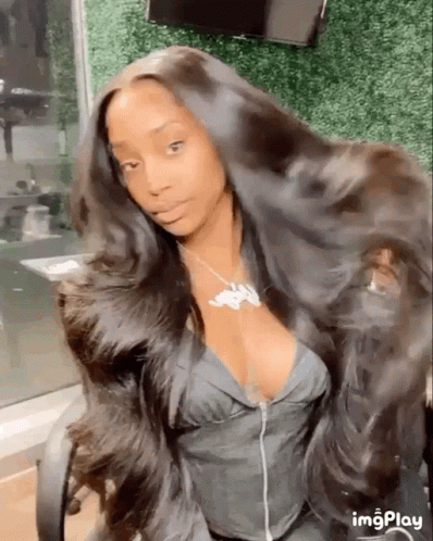 A Woman With Very Long Hair Is Sitting In A Chair And Looking At The Camera . GIF