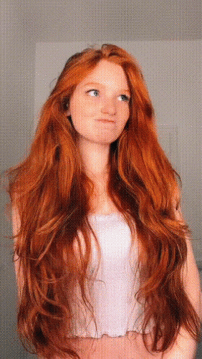 A Woman With Very Long Red Hair Is Wearing A White Top GIF