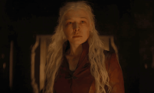 A Woman With White Hair And A Red Jacket Looks At The Camera GIF