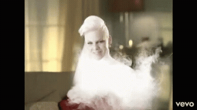 A Woman With White Hair Is Surrounded By Smoke And The Word Vevo Is On The Bottom Right GIF