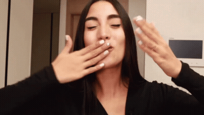 A Woman With White Nails Is Covering Her Mouth With Her Hand GIF