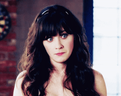 A Woman Without A Shirt Is Looking At The Camera With A Dart Board In The Background GIF