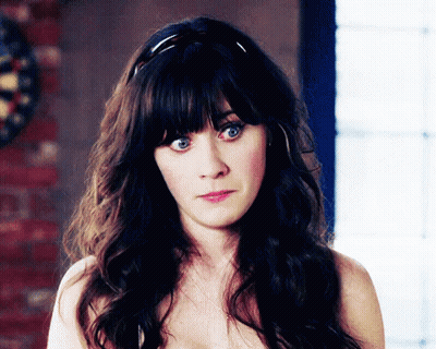 A Woman Without A Shirt Is Looking At The Camera With A Dart Board In The Background GIF