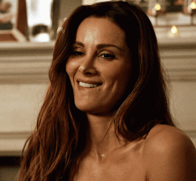A Woman Without A Shirt Is Smiling And Looking To The Side GIF