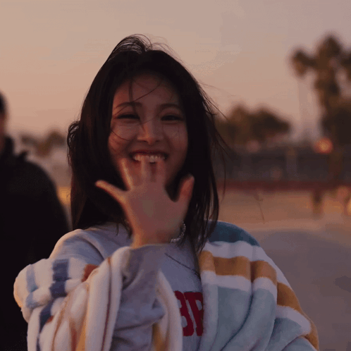 A Woman Wrapped In A Striped Blanket With The Letter Sp On It GIF