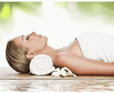 A Woman Wrapped In A Towel Is Laying On A Wooden Table GIF