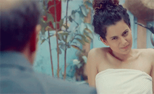 A Woman Wrapped In A White Towel Looks At The Camera GIF