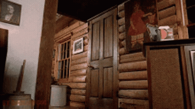 A Wooden Cabin With A Painting On The Wall Above The Door GIF