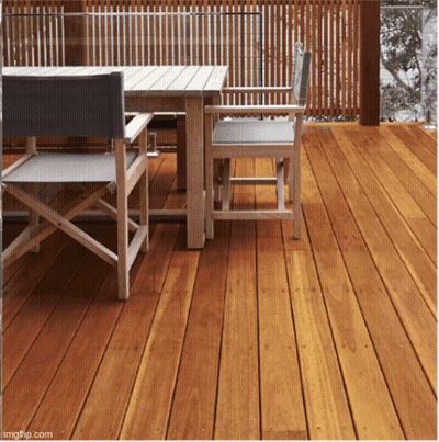 A Wooden Deck With A Table And Chairs And A Fence Behind It GIF