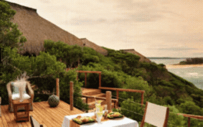 A Wooden Deck With A Table And Chairs Overlooking A Body Of Water GIF