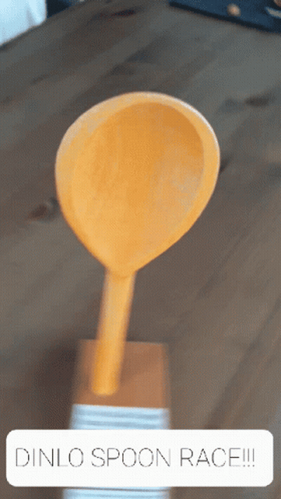 A Wooden Spoon Is On A Wooden Table With The Words Dinlo Spoon Race Written Below It GIF