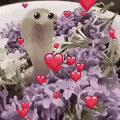 A Worm Is Sitting In A Pile Of Purple Flowers Surrounded By Hearts . GIF