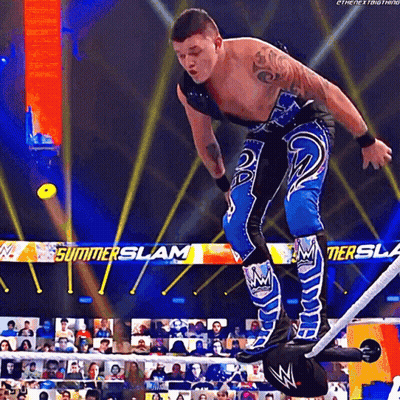 A Wrestler In A Blue And Black Outfit Is Standing On A Rope In Front Of A Banner That Says Summerslam GIF