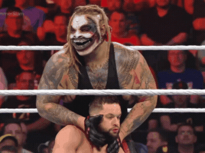 A Wrestler In A Clown Mask Is Holding Another Wrestler In A Ring With A Hammerslam Logo In The Background GIF