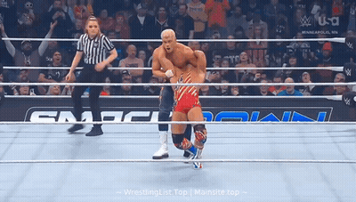 A Wrestler In A Red White And Blue Outfit Is In A Ring With A Referee . GIF