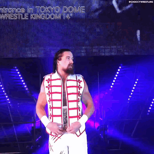 A Wrestler In A White And Red Outfit Is Holding A World Heavyweight Wrestling Championship Belt GIF