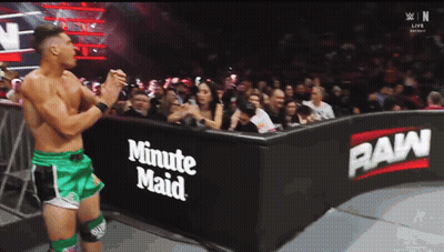 A Wrestler In Green Shorts Stands In Front Of A Sign That Says Minute Maid GIF