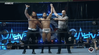 A Wrestler Is Being Congratulated By Another Wrestler In The Ring GIF