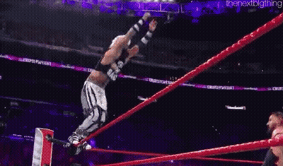 A Wrestler Is Being Lifted In The Air By Another Wrestler In A Ring . GIF
