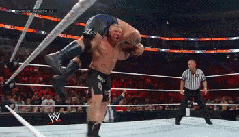 A Wrestler Is Carrying Another Wrestler On His Back In A Wrestling Ring GIF