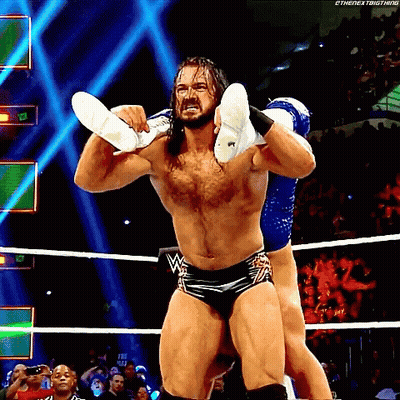 A Wrestler Is Carrying Another Wrestler On His Shoulders During A Match GIF