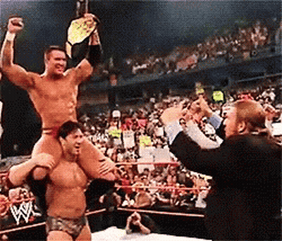 A Wrestler Is Carrying Another Wrestler On His Shoulders In A Ring GIF