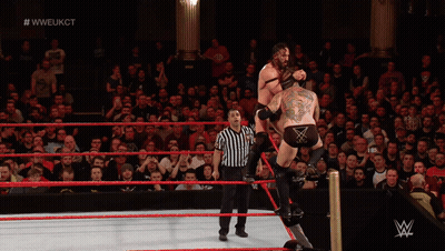 A Wrestler Is Doing A Flip In A Wrestling Ring With The Hashtag #WWE On The Bottom GIF