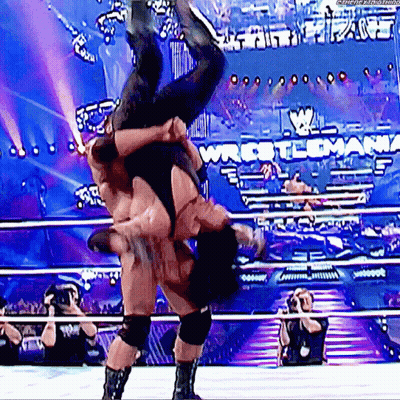 A Wrestler Is Doing A Flip Over Another Wrestler In A Wrestling Ring GIF