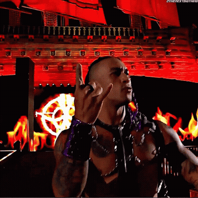 A Wrestler Is Giving The Middle Finger In Front Of A Red Background That Says Thenextbigthing GIF