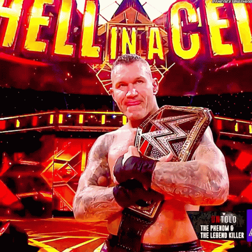 A Wrestler Is Holding A Wrestling Belt In Front Of A Sign That Says Hell In A Cell GIF