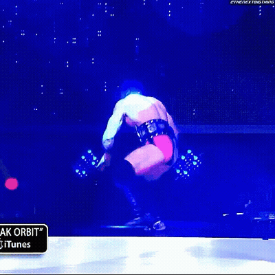 A Wrestler Is Jumping In The Air In Front Of A Sign That Says " Itunes " GIF
