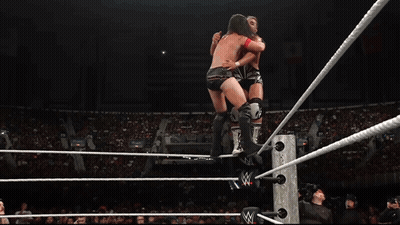 A Wrestler Is Jumping Over A Rope In A Wrestling Ring With A Crowd Watching GIF