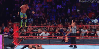 A Wrestler Is Jumping Over Another Wrestler In A Wrestling Ring During A Match . GIF