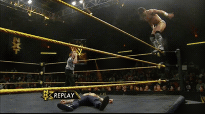 A Wrestler Is Jumping Over Another Wrestler In A Wrestling Ring With Replay On The Bottom Right GIF