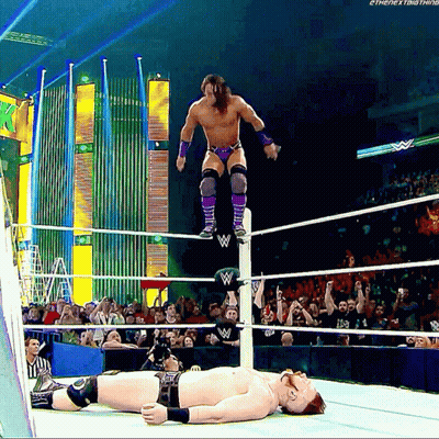 A Wrestler Is Jumping Over Another Wrestler Laying On The Ground GIF