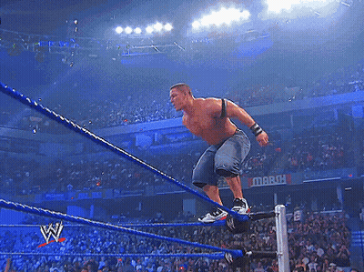 A Wrestler Is Jumping Over The Ropes In Front Of A Crowd With A Sign That Says March GIF
