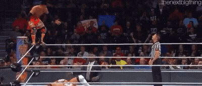 A Wrestler Is Jumping Over The Ropes While A Referee Watches GIF