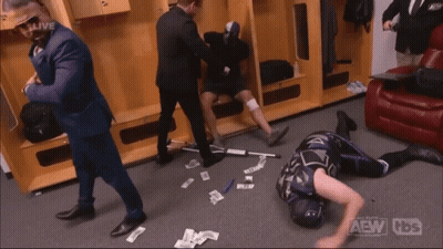 A Wrestler Is Laying On The Floor In A Locker Room With The Aew Logo On The Bottom Right GIF
