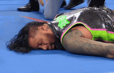 A Wrestler Is Laying On The Floor In A Wrestling Ring With His Eyes Closed . GIF